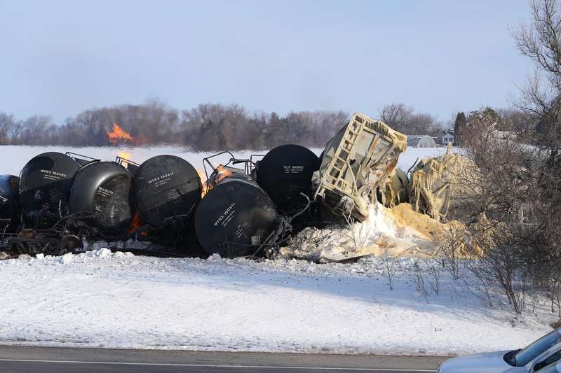 A pile of burning railway tank cars stretched across a snowy field.