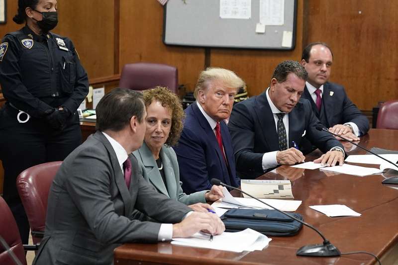 Trump sits in a courtroom flanked by attorneys. 